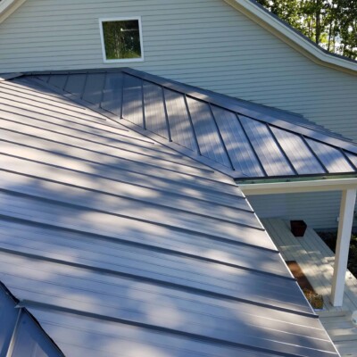 Light grey house with grey siding and a blue metal roof.